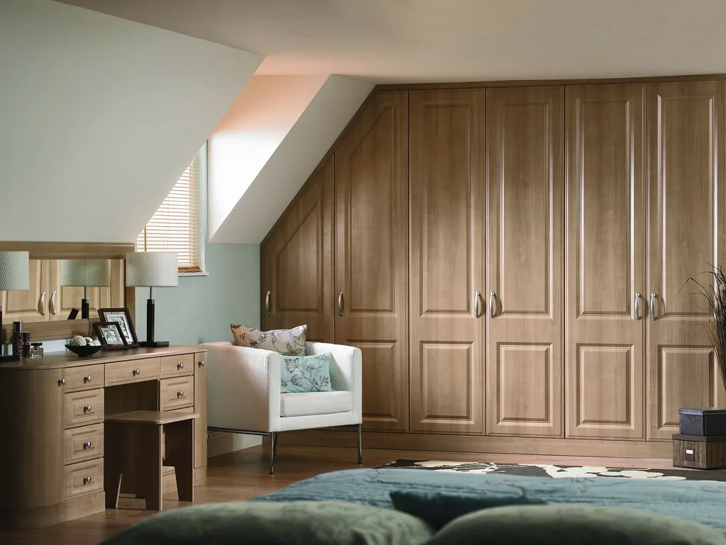 Raumhoher Einbauschrank aus Esche in einer Altbauwohnung, an eine schräge Dachwand angepasst, mit grifflosen Fronten
